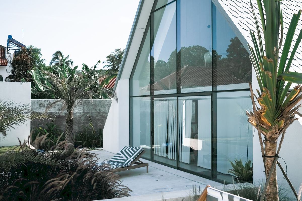Tall dark-framed aluminium glazing on a modern villa with palms