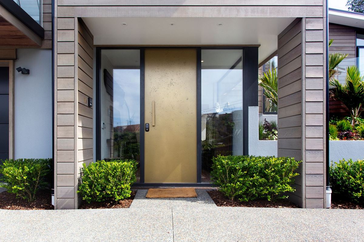 Modern villa entrance with a tall front door and glazed side panels