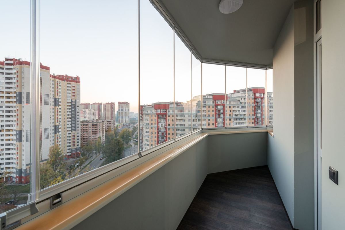 Apartment balcony enclosed with frameless glass panels overlooking the city