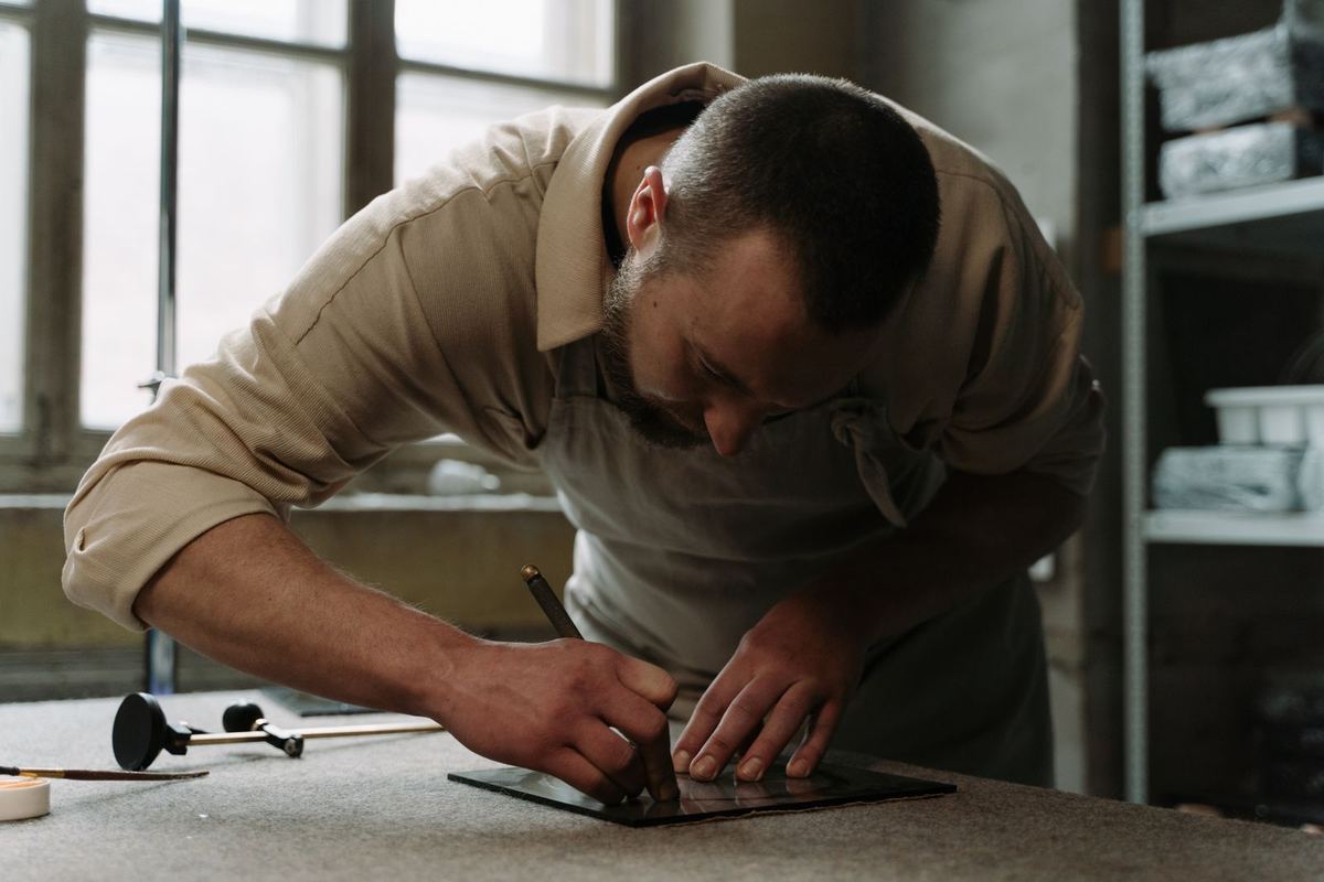 Glazier measuring and cutting a pane of glass on a workbench