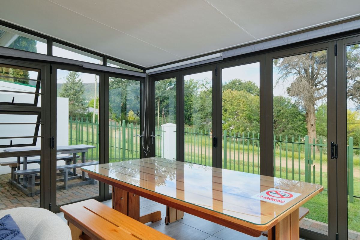 Terrace enclosed with dark aluminium-framed glazing around a dining table
