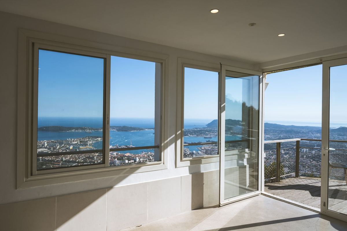 White-framed windows and a balcony door in a bright room overlooking the sea